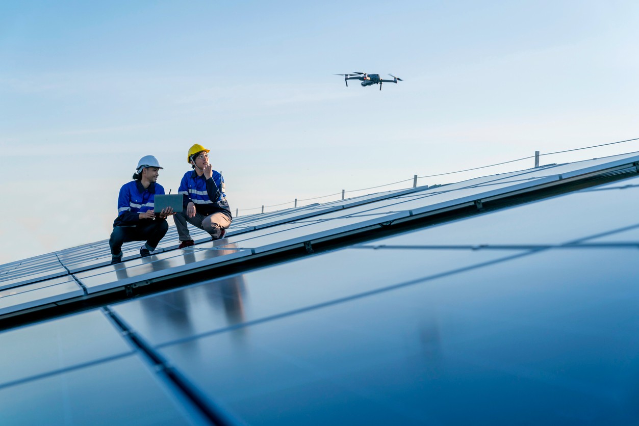 Workers using drone to check commercial solar panels.